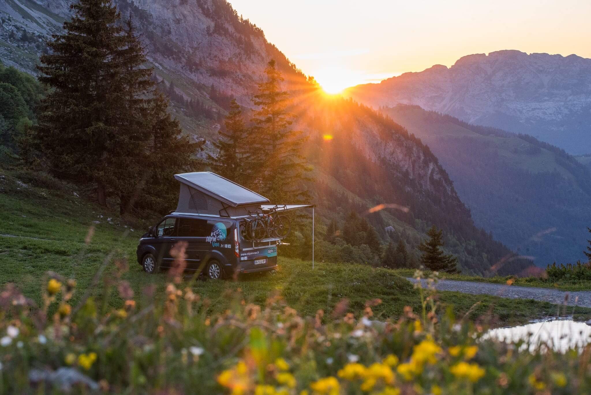 Van dans une prairie devant un coucher de soleil
