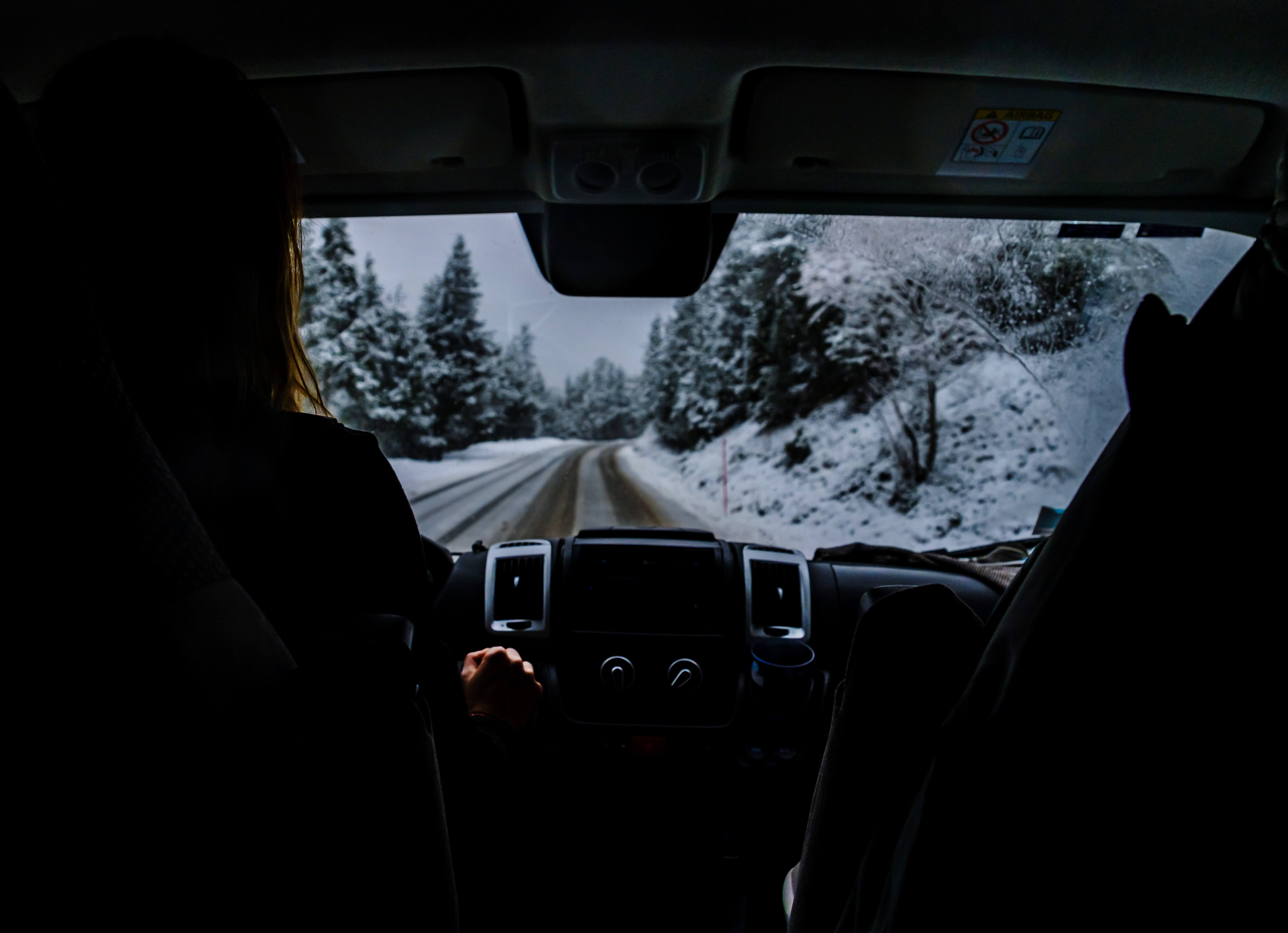 Femme conduisant un van sur une route enneigée